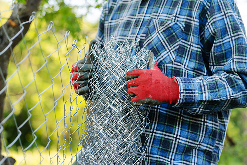 person removing chain-link fence