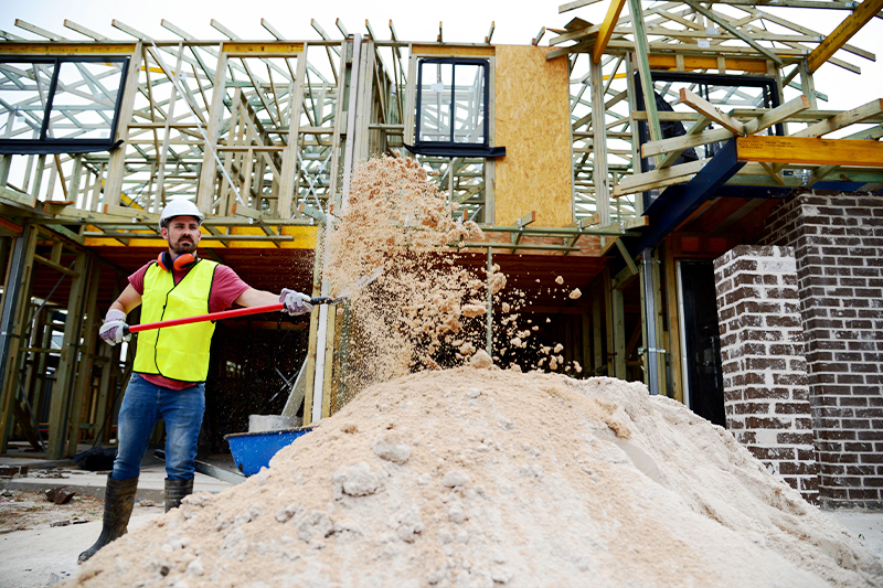 Construction worker shovelling sand