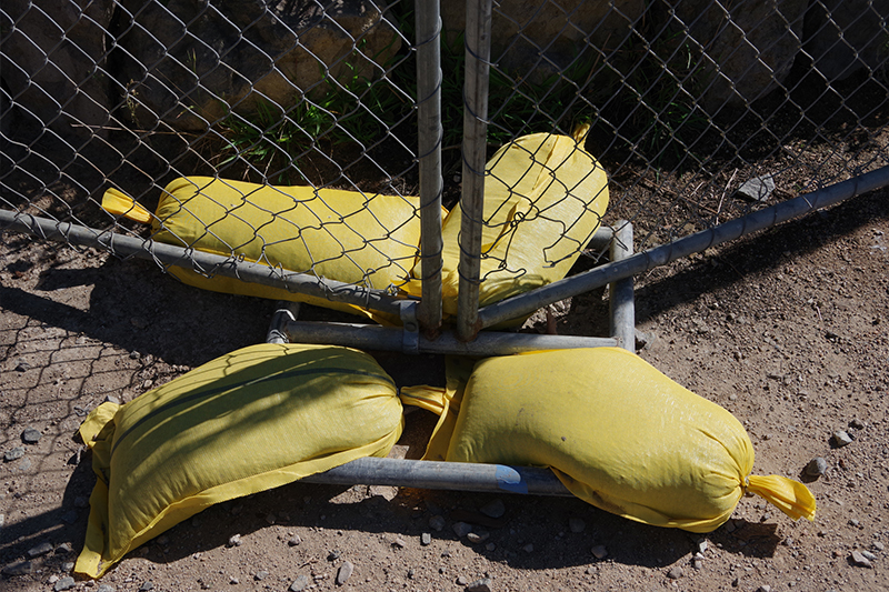 four sandbags being used to stabilize a single fence panel